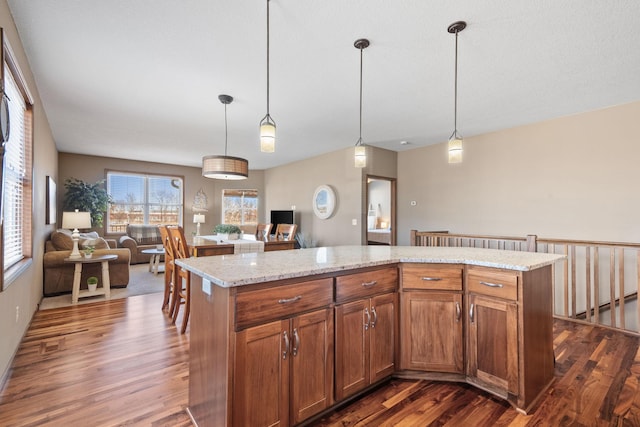 kitchen with dark wood finished floors, open floor plan, brown cabinets, and a kitchen island