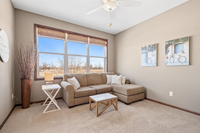 living area with baseboards, light colored carpet, and ceiling fan