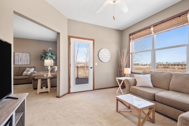 living room featuring baseboards, light colored carpet, and a ceiling fan