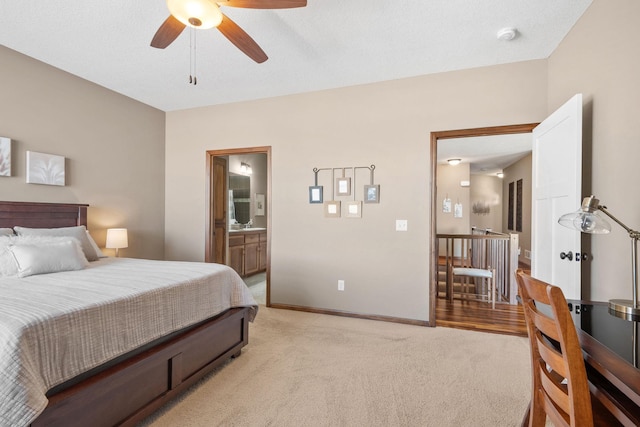 bedroom with a ceiling fan, light colored carpet, baseboards, and connected bathroom