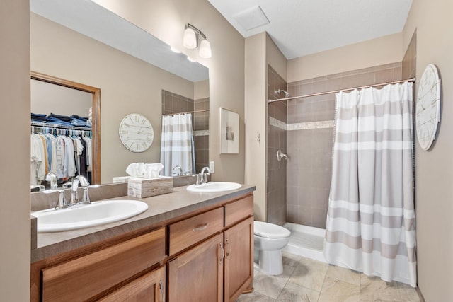 bathroom featuring a sink, tiled shower, and double vanity