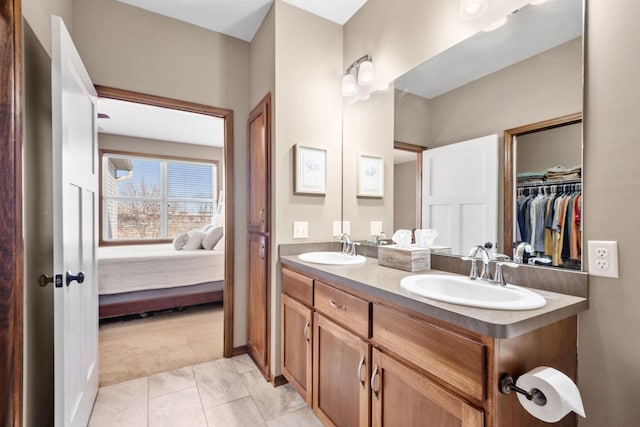 ensuite bathroom with a sink, ensuite bath, double vanity, and tile patterned flooring