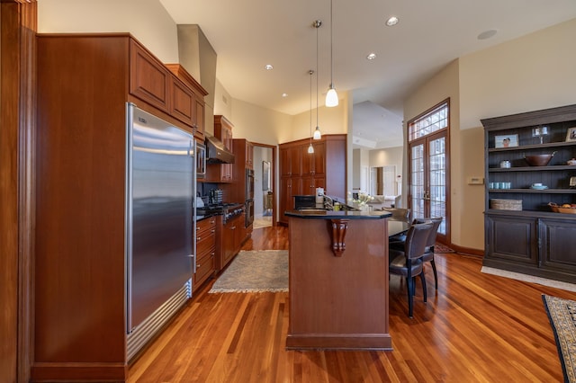 kitchen featuring stainless steel appliances, dark hardwood / wood-style floors, a center island, a kitchen bar, and decorative light fixtures