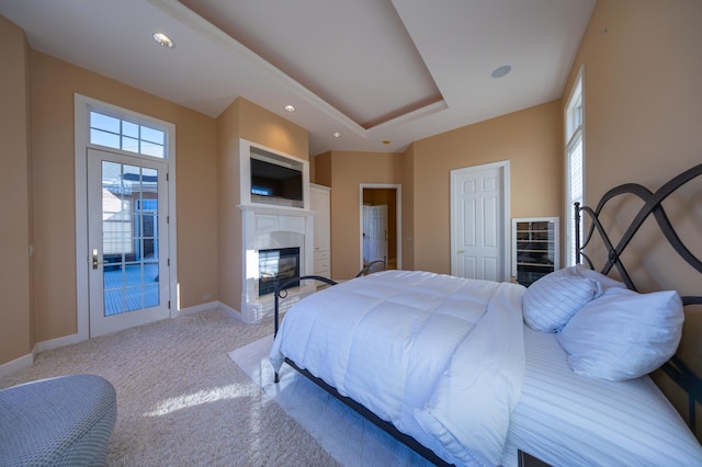 bedroom featuring a raised ceiling, light carpet, and access to outside