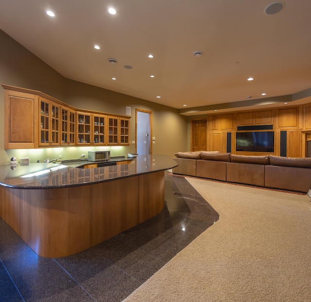 kitchen featuring dark stone counters, kitchen peninsula, and sink