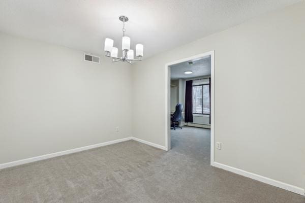 empty room featuring carpet flooring and a chandelier