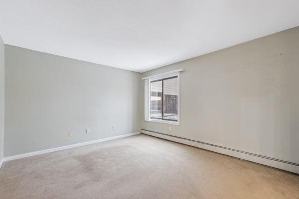 carpeted empty room with baseboard heating