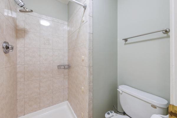 bathroom with a tile shower and toilet