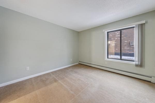 carpeted spare room with baseboard heating