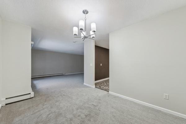 carpeted empty room with an inviting chandelier and baseboard heating