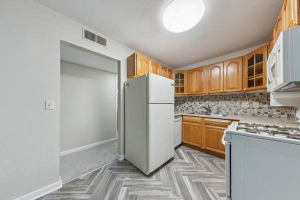 kitchen featuring tasteful backsplash, sink, white appliances, and light parquet floors