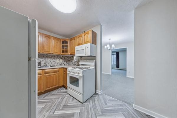 kitchen featuring sink, white appliances, tasteful backsplash, a notable chandelier, and light parquet flooring