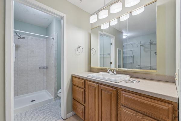 bathroom featuring tiled shower, vanity, toilet, and tile patterned floors