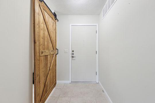 doorway to outside with a barn door, light tile patterned floors, and a textured ceiling