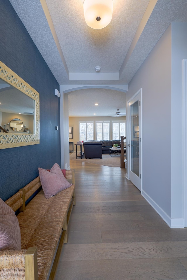 hallway with hardwood / wood-style flooring and a raised ceiling