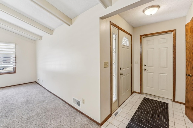 tiled entrance foyer with vaulted ceiling with beams and a textured ceiling