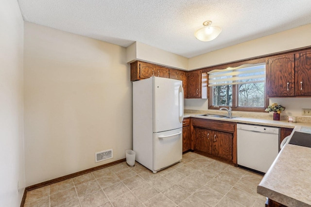 kitchen with sink, a textured ceiling, and white appliances