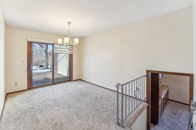 spare room with an inviting chandelier and carpet flooring