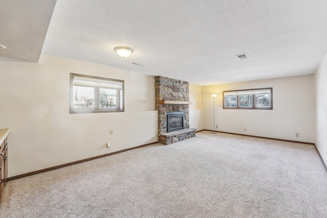 unfurnished living room featuring carpet floors, a textured ceiling, and a fireplace