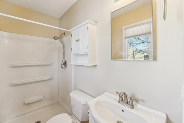 bathroom featuring sink, a shower, and toilet