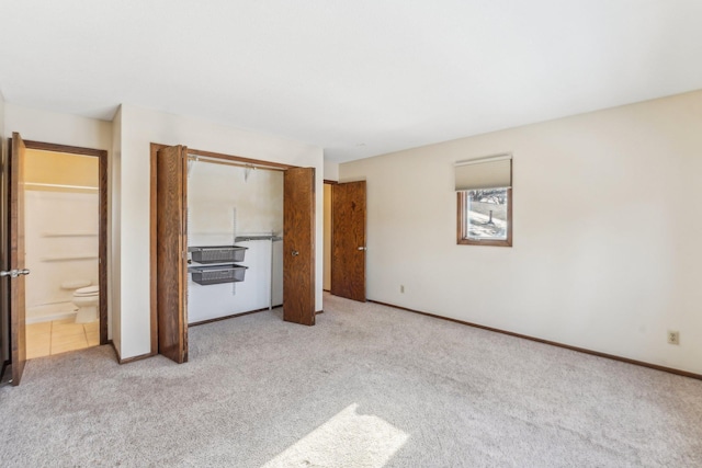 unfurnished bedroom with ensuite bath, light carpet, and a closet