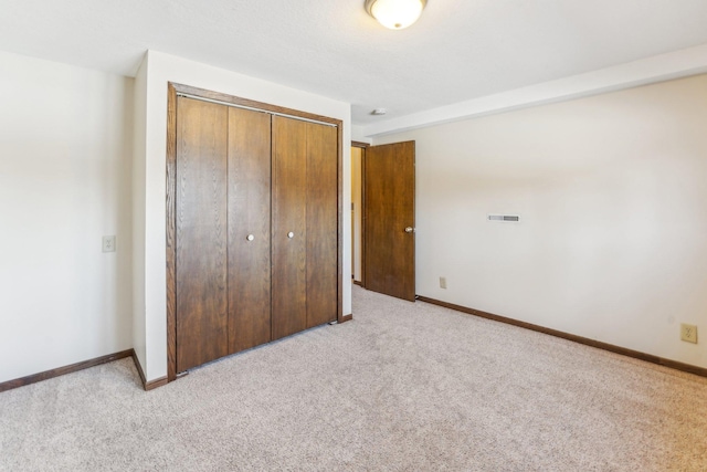 unfurnished bedroom featuring light colored carpet and a closet