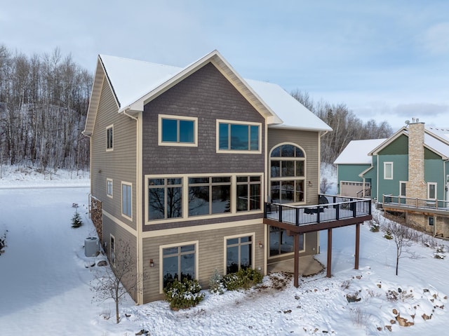 snow covered back of property featuring a wooden deck and central AC