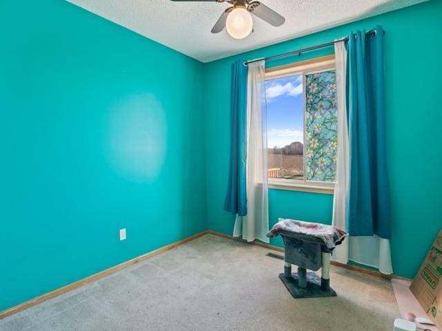 carpeted empty room with ceiling fan and a textured ceiling