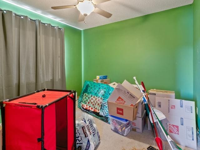 recreation room with carpet floors, a textured ceiling, and ceiling fan