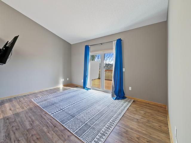 spare room featuring lofted ceiling, wood finished floors, and baseboards