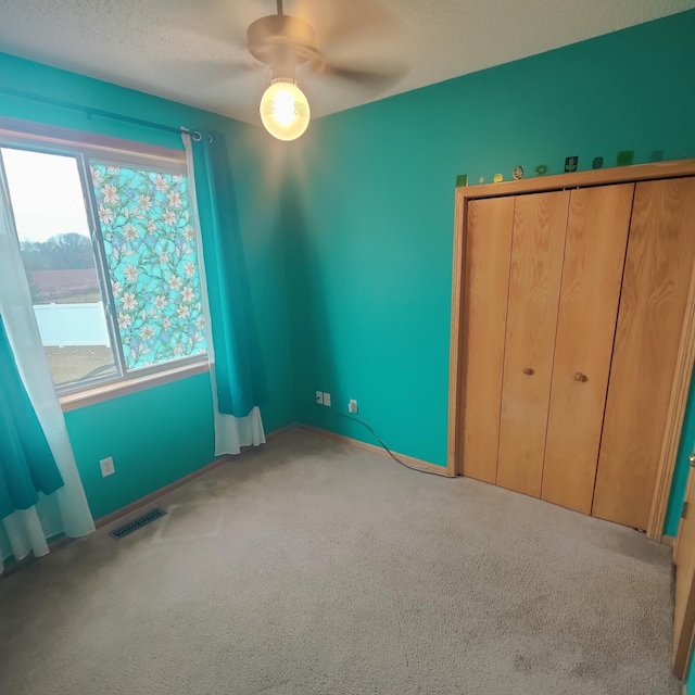 unfurnished bedroom featuring carpet floors, visible vents, and ceiling fan