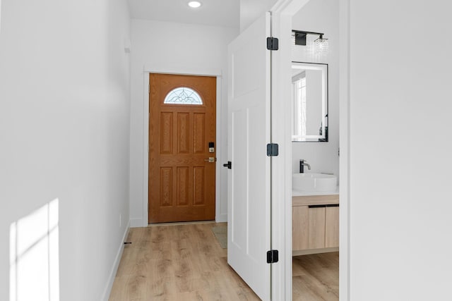 doorway to outside featuring sink and light wood-type flooring