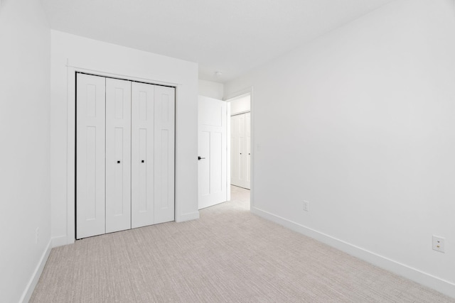 unfurnished bedroom with light colored carpet and a closet