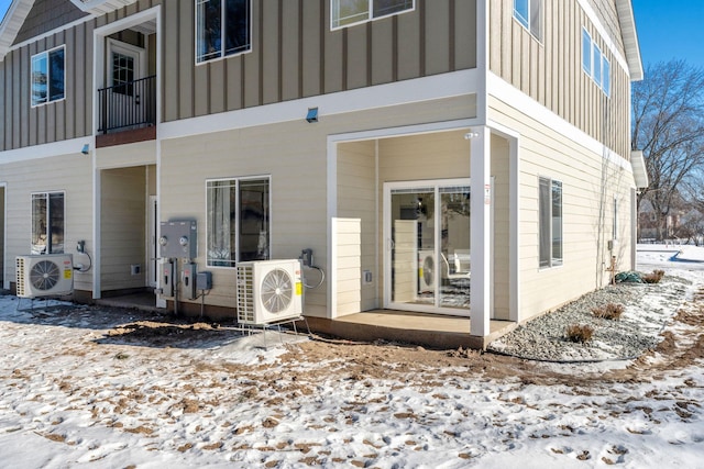 snow covered property entrance with ac unit