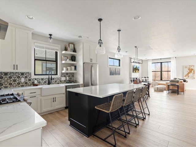 kitchen with sink, a breakfast bar area, white cabinetry, a kitchen island, and stainless steel appliances