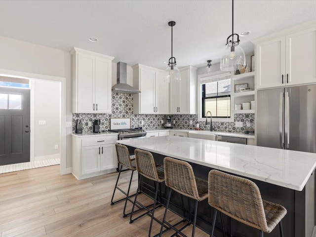 kitchen featuring white cabinetry, decorative light fixtures, wall chimney exhaust hood, and a kitchen island