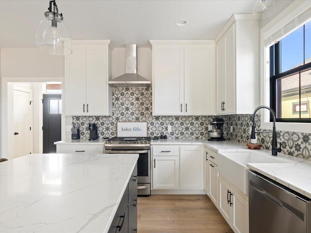 kitchen with white cabinetry, wall chimney exhaust hood, stainless steel appliances, and light stone counters