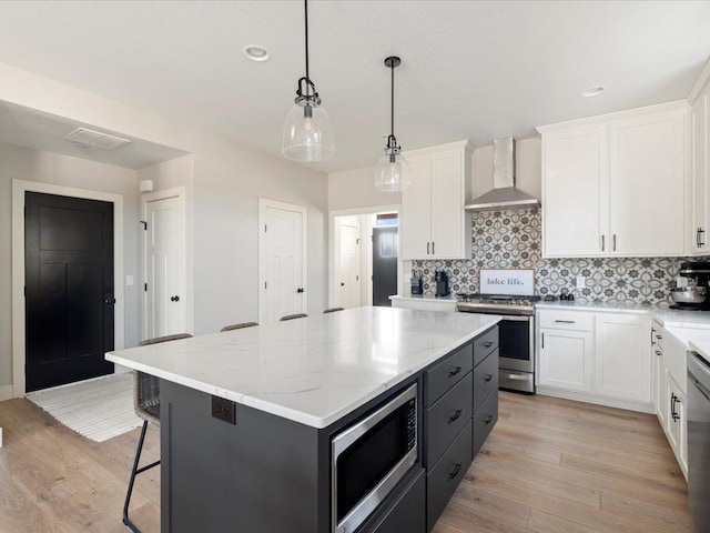 kitchen with wall chimney exhaust hood, a kitchen island, and white cabinets