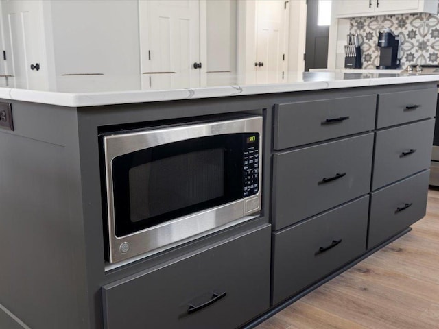 kitchen featuring backsplash, white cabinets, light wood-type flooring, and gray cabinetry