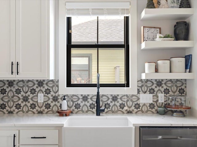 interior space featuring white cabinetry, stainless steel dishwasher, light stone countertops, and sink