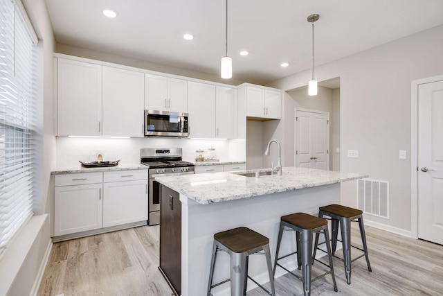 kitchen with pendant lighting, an island with sink, stainless steel appliances, and sink