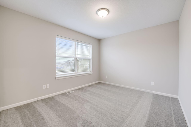 carpeted spare room with visible vents and baseboards