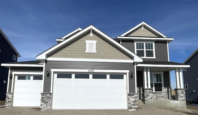 craftsman-style house featuring a garage, stone siding, and a porch