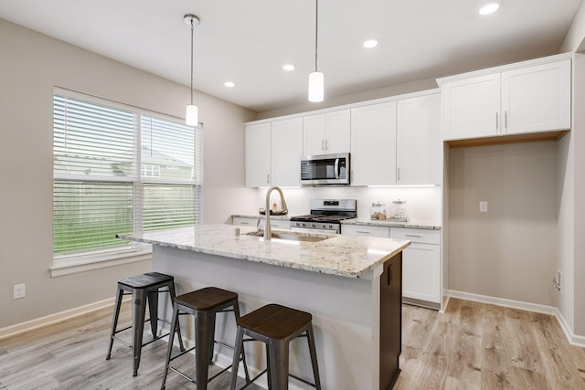 kitchen with tasteful backsplash, a center island with sink, appliances with stainless steel finishes, white cabinetry, and a sink