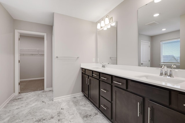 full bathroom featuring double vanity, visible vents, a walk in closet, and a sink