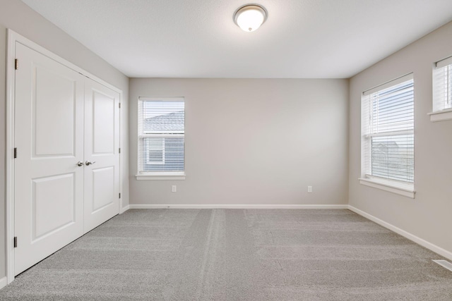 unfurnished room with baseboards, visible vents, and light colored carpet