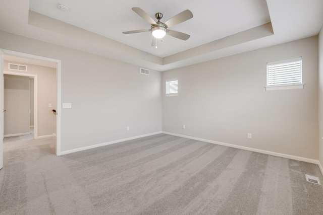 spare room featuring a healthy amount of sunlight, a raised ceiling, visible vents, and baseboards