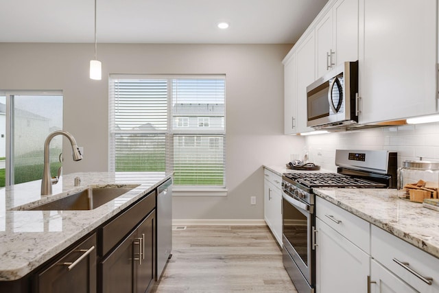 kitchen with appliances with stainless steel finishes, a healthy amount of sunlight, a sink, and backsplash