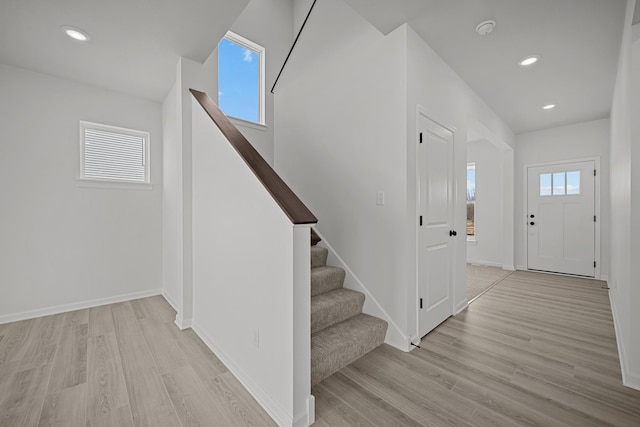 entryway with a wealth of natural light, stairway, baseboards, and wood finished floors