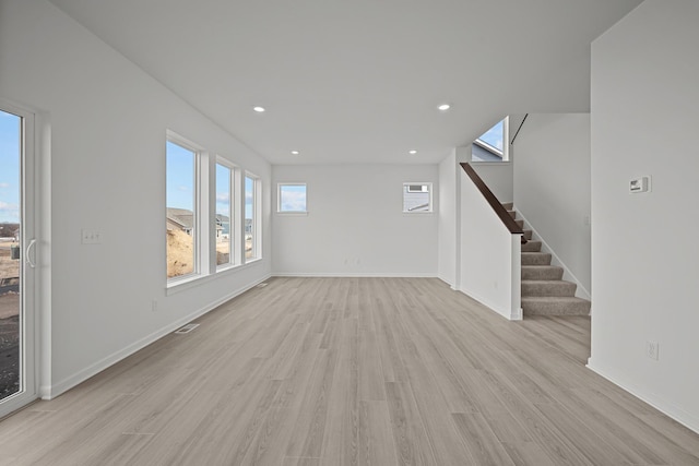 unfurnished living room with recessed lighting, light wood-style flooring, baseboards, and stairs